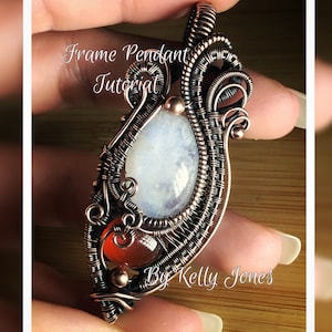 Peut inclure: Un pendentif en fil de fer avec une pierre de lune blanche et des pierres de cornaline rouges. Le pendentif est fait de fil de cuivre et a un design délicat et complexe. Le texte "Frame Pendant Tutorial By Kelly Jones" est visible sur l'image.