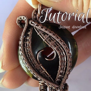 Könnte beinhalten: Ein Anhänger aus Kupferdraht, der einen dunkelgrünen und goldenen Stein mit einem Loch in der Mitte umwickelt. Der Anhänger wird von einer Hand gehalten und der Text "Tutorial Sofort-Download" ist über dem Anhänger sichtbar. Der Text "Kelly Jones Jewellery" ist unter dem Anhänger sichtbar.