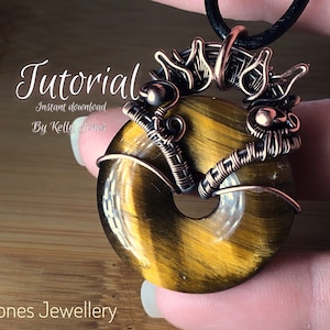 Könnte beinhalten: Eine Anleitung zum Erstellen eines drahtgewickelten Tigeraugen-Anhängers. Der Anhänger besteht aus einem runden Tigeraugen-Stein, der mit Kupferdraht umwickelt ist und eine dekorative Öse hat. Die Anleitung steht zum sofortigen Download bereit. "Tutorial Sofort-Download Von Kelly Jones"