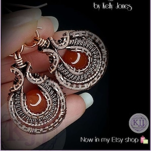 Peut inclure: Boucles d'oreilles en fil de cuivre enroulé avec une pierre de cornaline au centre. Les boucles d'oreilles sont faites à la main et ont un design unique. Les boucles d'oreilles s'appellent "Beatrix" et sont disponibles dans la boutique Etsy.