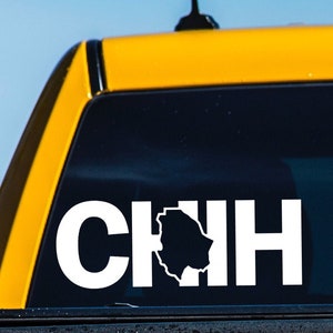 May include: A white vinyl sticker on a yellow truck bed with the text "CHIH" and a black silhouette of the state of Chihuahua, Mexico.