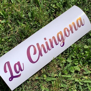 Pu&ograve; includere: Un adesivo bianco con il testo "La Chingona" in un font sfumato viola e arancione.