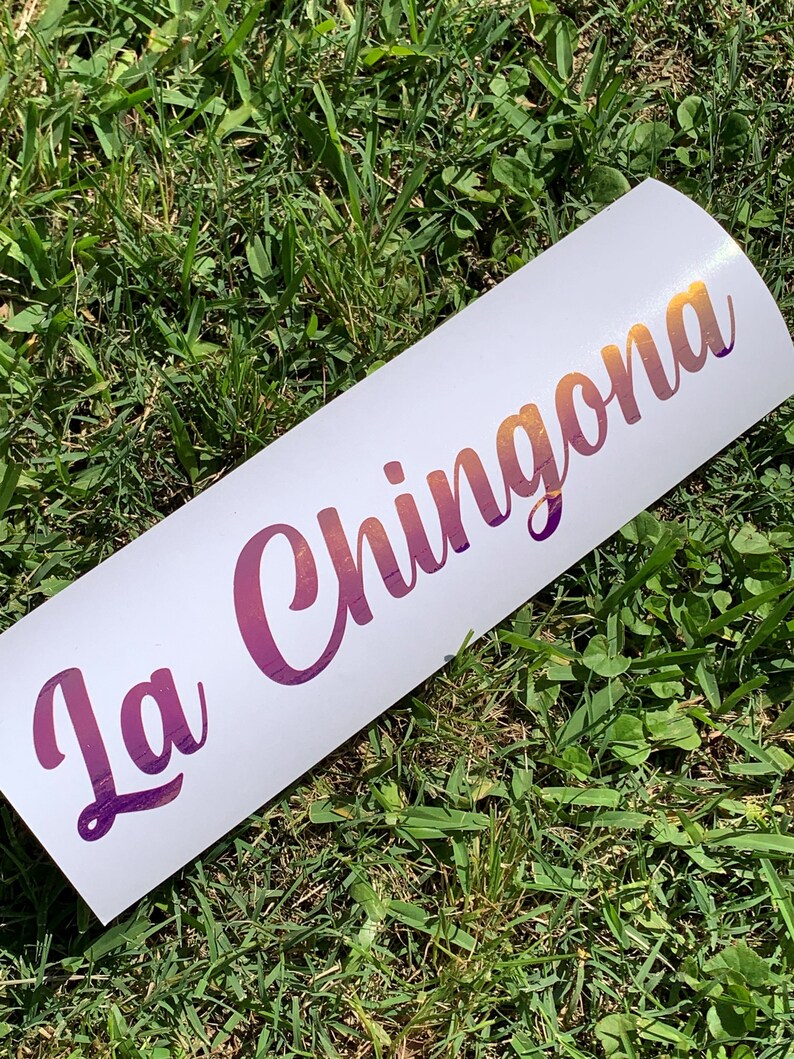 Pu&ograve; includere: Un adesivo bianco con il testo "La Chingona" in un font sfumato viola e arancione.