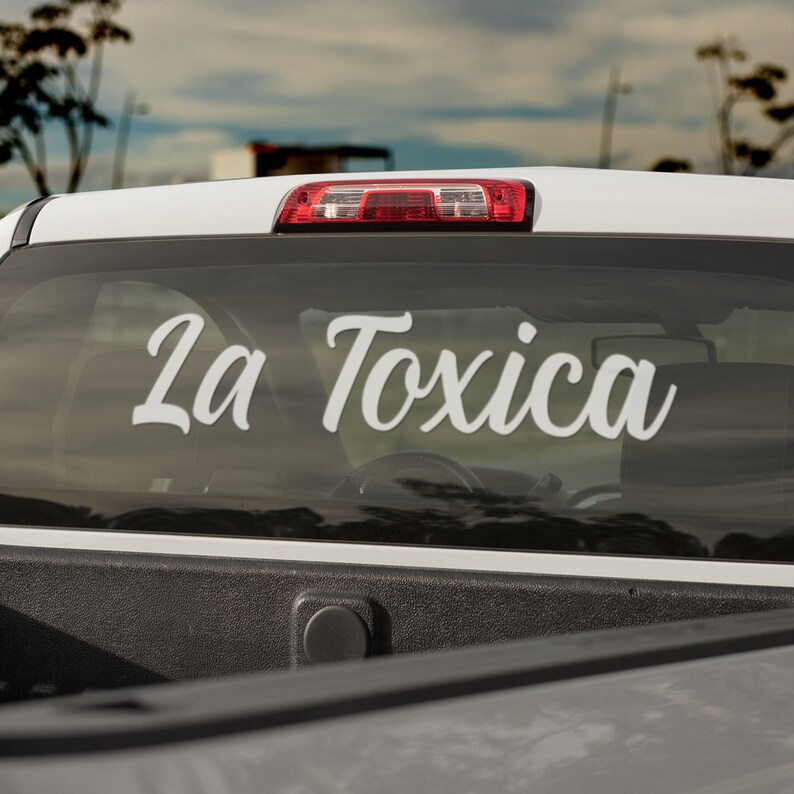 Pu&ograve; includere: Furgone bianco con un adesivo sul lunotto posteriore che dice "La Toxica" in un font corsivo.