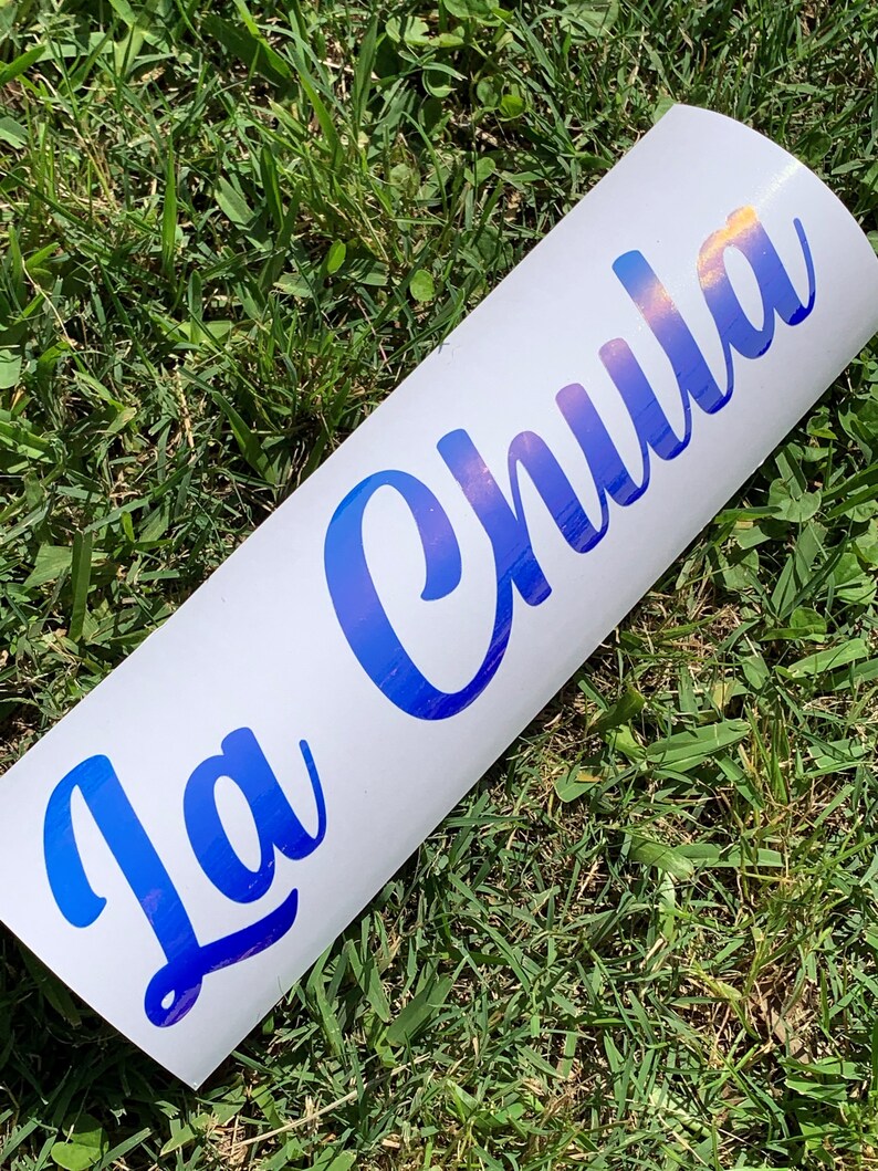 Pu&ograve; includere: Un adesivo in vinile bianco con il testo "La Chula" in lettere blu iridescenti.