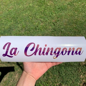Pu&ograve; includere: Adesivo in vinile bianco con il testo "La Chingona" in un font sfumato viola e rosa.