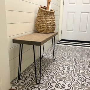 May include: A wooden bench with a natural finish and black hairpin legs. A woven basket sits on the bench, and the bench is placed on a patterned tile floor. The bench is approximately 36 inches long.