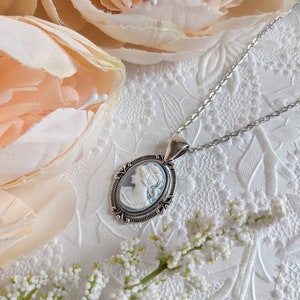 Cameo necklace. Silver Oval setting with flourishes on a stainless steel chain. The cameo is of a Greek Goddess with a light blue background and detailed white relief.