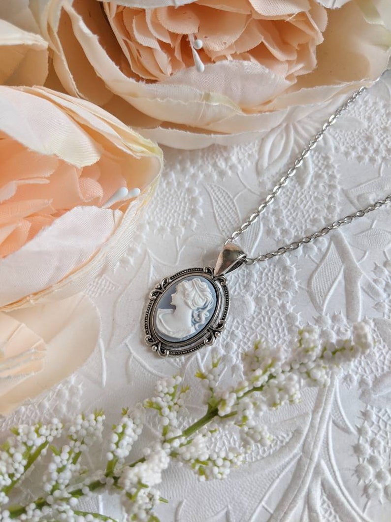 Cameo necklace. Silver Oval setting with flourishes on a stainless steel chain. The cameo is of a Greek Goddess with a light blue background and detailed white relief.