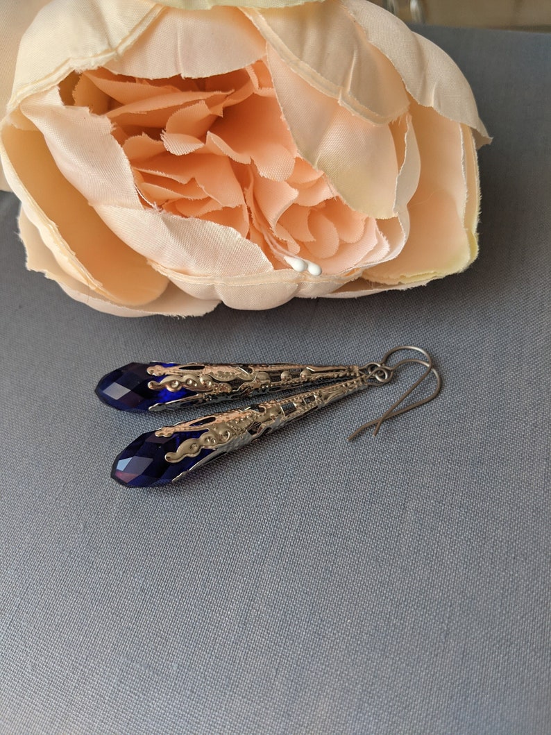 Vintage Style earrings with long silver tone filigree bead caps over sapphire blue faceted glass beads.