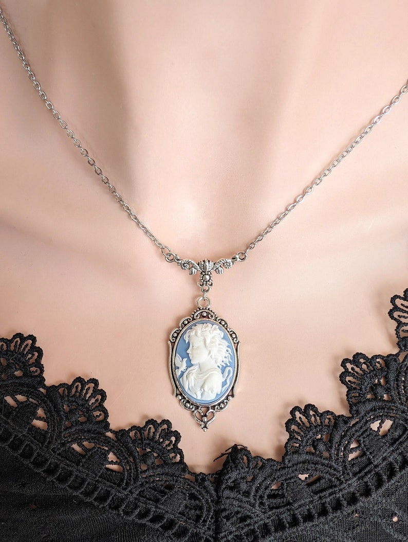 A close up of a neckline showing a blue and white cameo necklace with an ornate silver pendant and tulip connector.