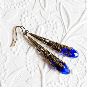 Vintage Style earrings with long silver tone filigree bead caps over sapphire blue faceted glass beads.