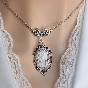 Ornate silver Cameo necklace with white and wine cameo displayed on Woman's neckline.