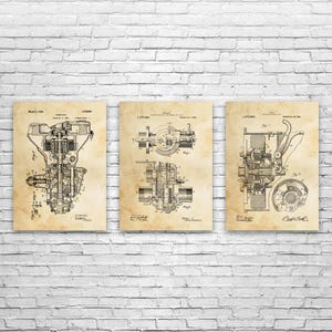 May include: Set of three vintage-style prints featuring detailed black and white diagrams of mechanical components. The prints have a sepia-toned background, resembling aged paper, and are mounted on a white brick wall.