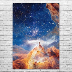 May include: A vibrant print of a nebula with a deep blue sky filled with stars. The image features orange and brown cloud formations and a bright cluster of stars in the center. This celestial artwork is perfect for space enthusiasts.