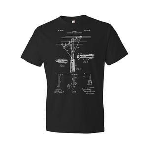 May include: Black t-shirt with a white print of a vintage patent drawing for a telephone system. The drawing shows a pole with wires and a device labeled "Fig. 1". The patent number is 700,589 and the date is May 20, 1902.