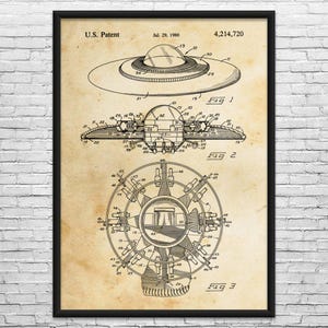 May include: A framed patent illustration of a flying saucer, dated July 29, 1980. The diagram shows top, side, and bottom views of the spacecraft, with detailed technical drawings and labels. The background is a vintage parchment color.