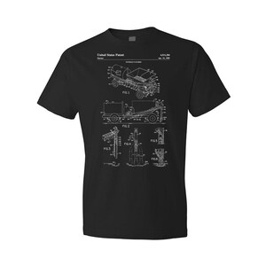 May include: Black t-shirt with a white print of a patent drawing for a "Vehicle Loading System". The patent number is 4,811,284 and the date is Apr. 15, 1989. The drawing shows a truck with a loading system for moving objects.