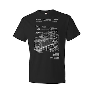 May include: Black t-shirt with a white print of a patent drawing for a "Magnetic Tape Cartridge". The patent number is 3,854,186 and the date is Sept. 27, 1980.