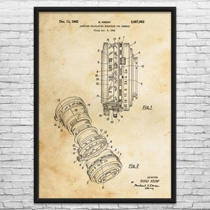 May include: A framed vintage patent print of a camera aperture calculating structure, dated December 11, 1962. The sepia-toned print features detailed technical drawings of camera components, including lenses and aperture mechanisms.