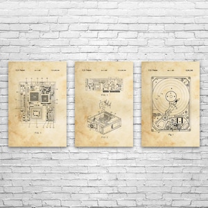 May include: Three framed vintage-style prints featuring computer hardware schematics. The prints, in sepia tones, depict a motherboard, a computer case, and a hard drive, each labeled with diagrams and patent information. The prints are mounted on a white brick wall.