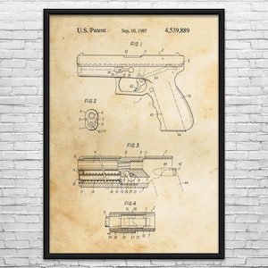 May include: A framed patent illustration of a handgun, dated September 10, 1985, with the patent number 4,539,889. The diagram includes detailed views of the firearm's components, labeled with numbers and technical annotations. The print has a vintage, aged paper appearance.
