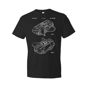 May include: Black t-shirt with a white outline of a patent drawing for a pair of goggles. The drawing shows two different views of the goggles. The text on the shirt reads "U.S. Patent, Feb. 1, 2000, Des. 405,124, Fig. 1, Fig. 2".