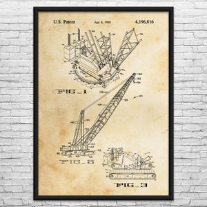 May include: Framed patent print of a crane, dated April 8, 1980. The black and white technical drawing shows three different views of the crane, labeled as Fig. 1, Fig. 2, and Fig. 3. The print is on a beige background.