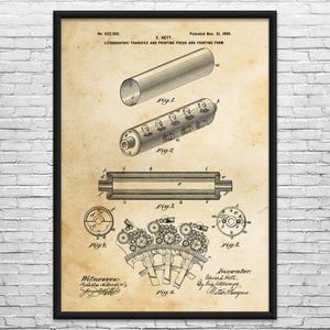 May include: Framed vintage patent print of a lithographic transfer and printing press. The sepia-toned print features detailed technical drawings of the press components, including rollers and gears, with the inventor's name and patent information.