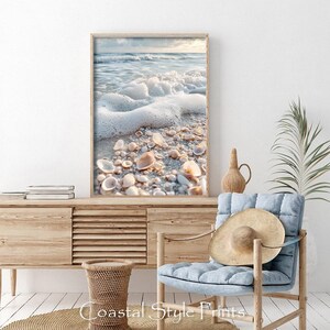 May include: A framed photograph of a beach scene with white foamy waves crashing on the shore. The sand is covered in seashells and the water is a light blue color.