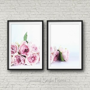 May include: Two black framed prints of pink roses on a white background. The roses are arranged in a bouquet and are in focus. The background is blurred.