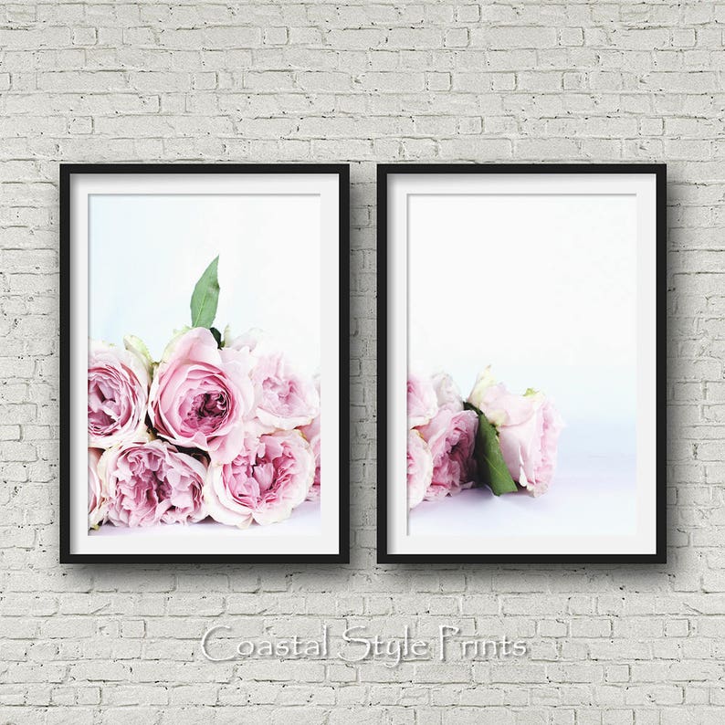 May include: Two black framed prints of pink roses on a white background. The roses are arranged in a bouquet and are in focus. The background is blurred.
