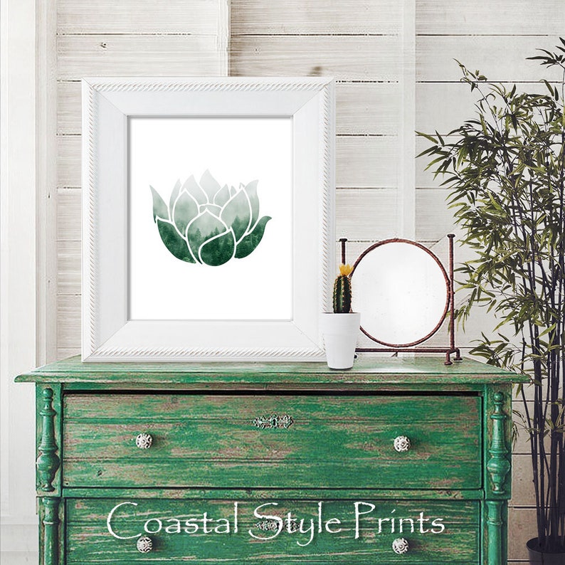 May include: A white frame with a green watercolor print of a lotus flower. The print is on a green dresser with a small cactus plant in a white pot and a round mirror on the dresser.