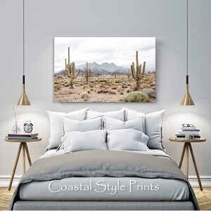 May include: A photograph of a desert landscape with tall cacti and mountains in the background. The sky is cloudy and the ground is dry and sandy.
