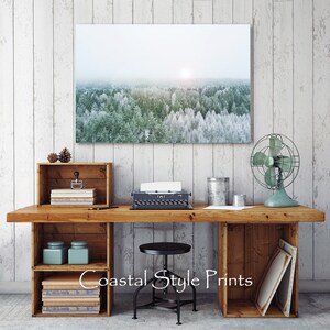 May include: A rustic wooden desk with two open shelves on each side, a vintage typewriter, a small fan, and a framed photograph of a snowy forest landscape. The desk is set against a white wood panel wall.