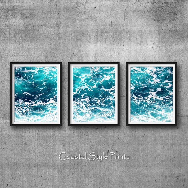May include: Three framed prints showcasing a vibrant ocean scene. The artwork captures the turquoise and deep blue hues of the water, with white foamy waves. The phrase "Coastal Style Prints" is written in a cursive font at the bottom.
