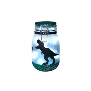 May include: A green glass jar with a metal lid and a silhouette of a dinosaur inside. The jar is lit from within with white lights. The jar has the text "'s Boutique" on the bottom.