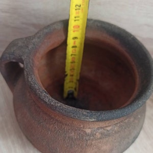 May include: A terracotta pot with a handle, measuring 14 inches in diameter. The pot is brown and has a rough texture.