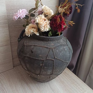 May include: A dark brown ceramic vase with a woven pattern, filled with a bouquet of pink, white, and red flowers.