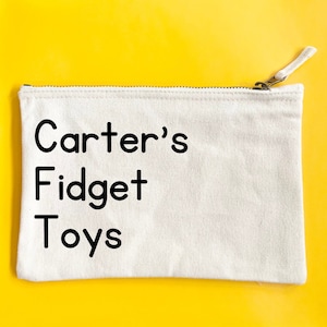 May include: White canvas zippered pouch with black text that reads "Carter's Fidget Toys".