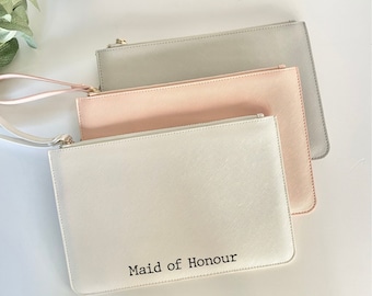 May include: Three zippered pouches in different colors: gray, pink, and white. The white pouch has the text "Maid of Honour" printed on it.