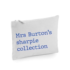 May include: White canvas zippered pouch with blue embroidered text that reads "Mrs. Burton's sharpie collection"