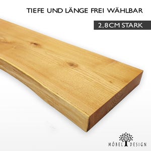 Può includere: Un ripiano in legno naturale con un bordo vivo, spesso 2,8 cm. Il ripiano è realizzato in legno massello e ha una finitura naturale. Il testo "Tiefe und Länge frei wählbar 2,8CM stark" è visibile nell'immagine.