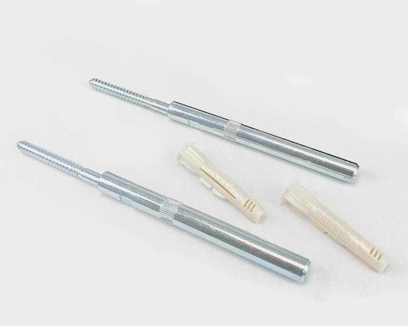 Może przedstawiać: Dwa srebrne metalowe wsporniki p&oacute;łek z gwintowanymi końcami i dwa kremowe plastikowe kołki ścienne. Wsporniki p&oacute;łek mają cylindryczny korpus.