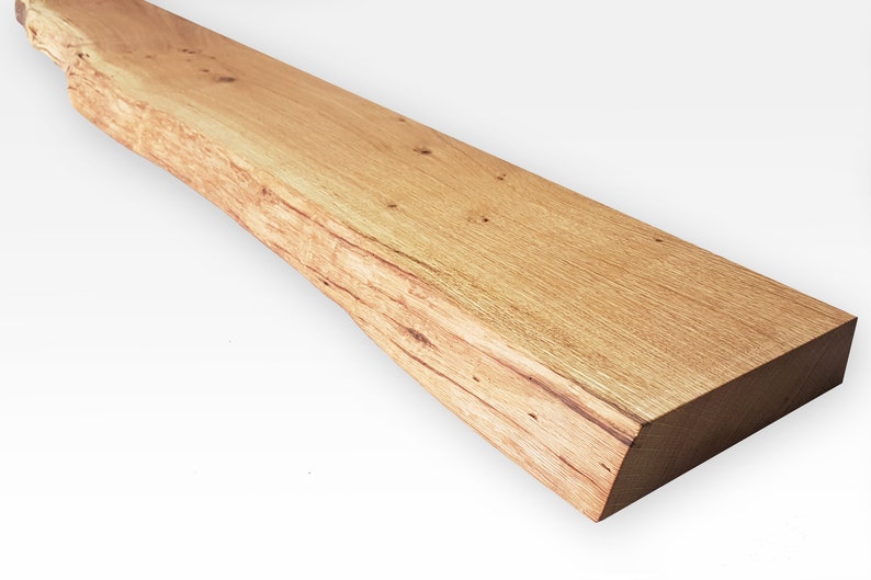 May include: A long, rustic wooden shelf with a natural, light brown finish. The shelf has a live edge on one side, giving it a unique and organic look.