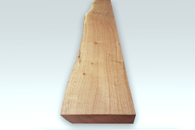 May include: A long, narrow piece of wood with a natural, light brown finish. The wood has a live edge on one side and a smooth, straight edge on the other. The wood is perfect for crafting projects or adding a rustic touch to your home decor.