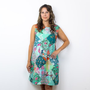 Könnte beinhalten: Ärmelloses Patchwork-Kleid in Türkis, Rosa und Orange. Das Kleid hat ein Blumenmuster und einen knielangen Saum. Das Model trägt schwarze Stiefeletten mit Nieten.