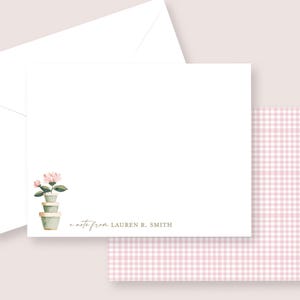 May include: White stationery set featuring a floral design and a pink gingham pattern. The set includes a folded card with a watercolor illustration of stacked flower pots and the text "a note from Lauren R. Smith."