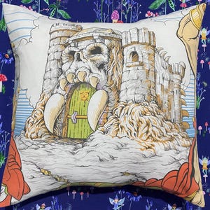 May include: Square decorative pillow featuring a detailed illustration of a castle with a skull-shaped entrance, a green door, and tall towers. The pillow has a white background with a blue and orange border.