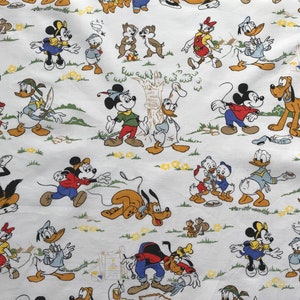 May include: White fabric with a repeating pattern of cartoon characters including Mickey Mouse, Donald Duck, Goofy, and Pluto. The characters are depicted in various poses and activities, such as walking, playing, and interacting with each other. The fabric is a light white with yellow accents.